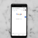 black Android smartphone showing google site on white surface